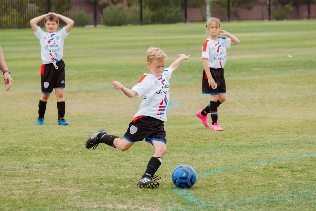 Young boy kicking a soccer ball on a grass field, representing the Messi sons' youth football careers