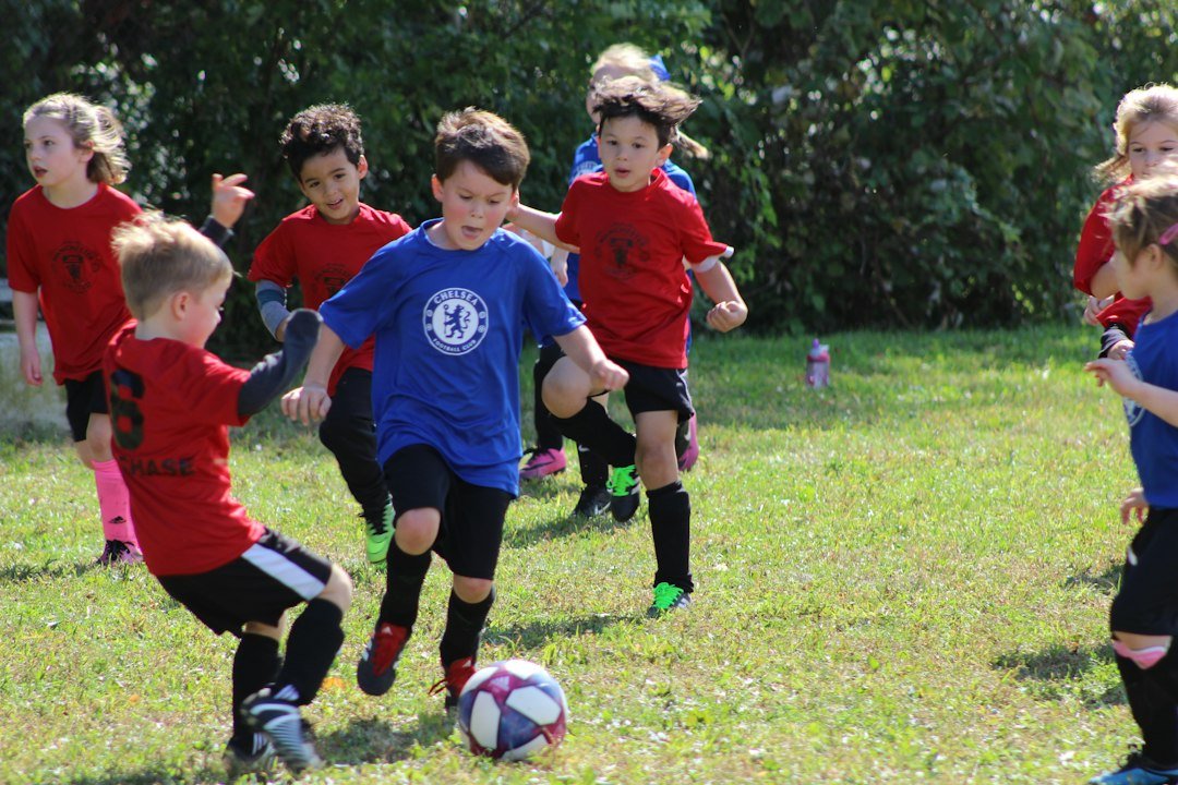 Boy in a red and blue jersey kicking a ball, illustrating young academy footballers like Mateo and Ciro Messi