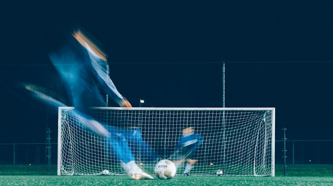 Goalkeeper diving as a player takes a shot during a football session